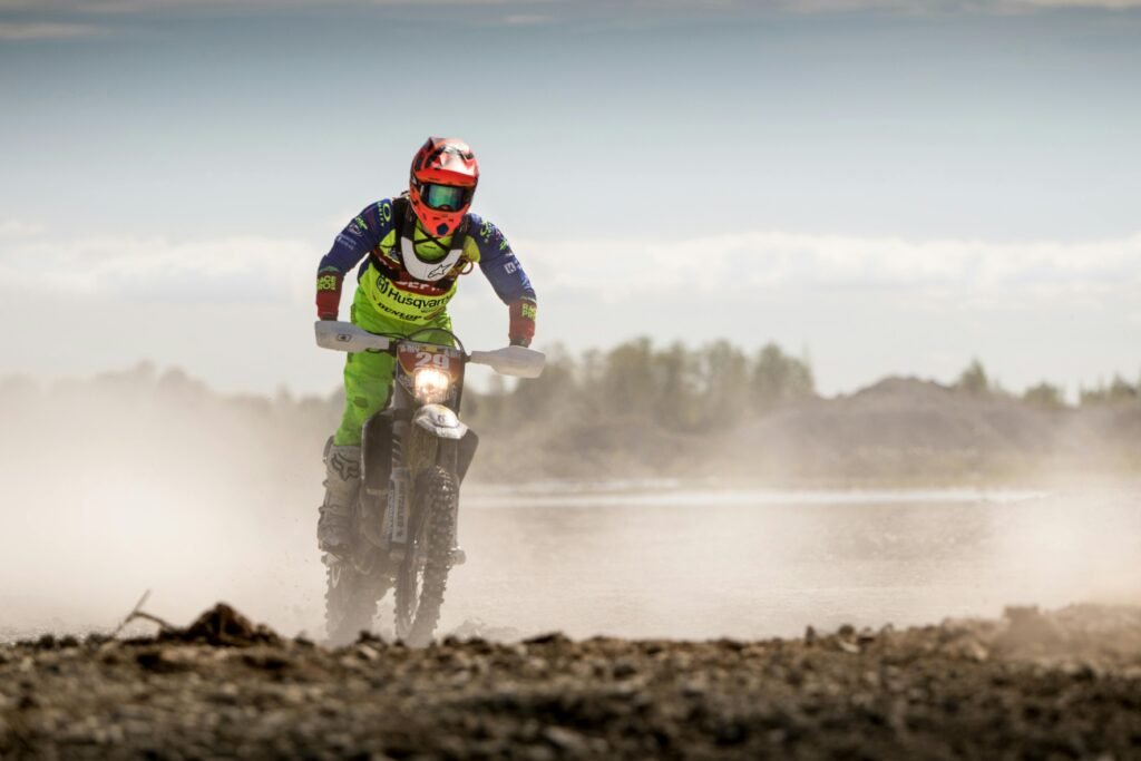 Dynamic offroad motorbike racing with dust trails in a rugged landscape.