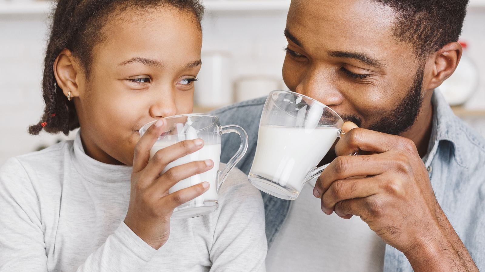 Father and daughter drinking milk together at home