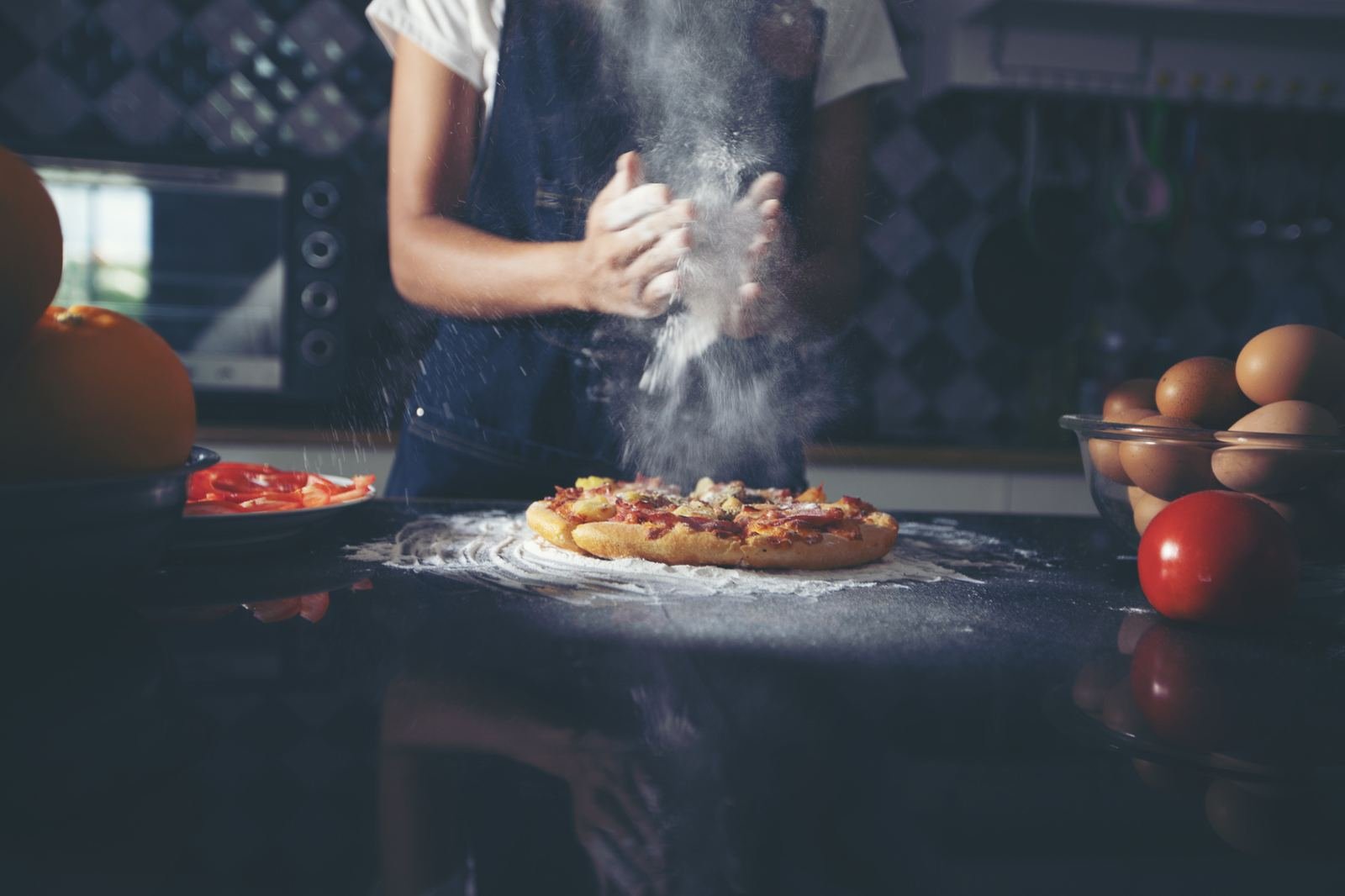 Hands preparing pizza dough in a home kitchen