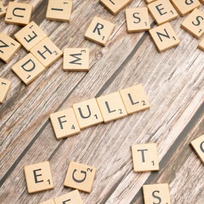 Scattered letter tiles on wood with the word 'FULL' spelled out, conveying abundance.